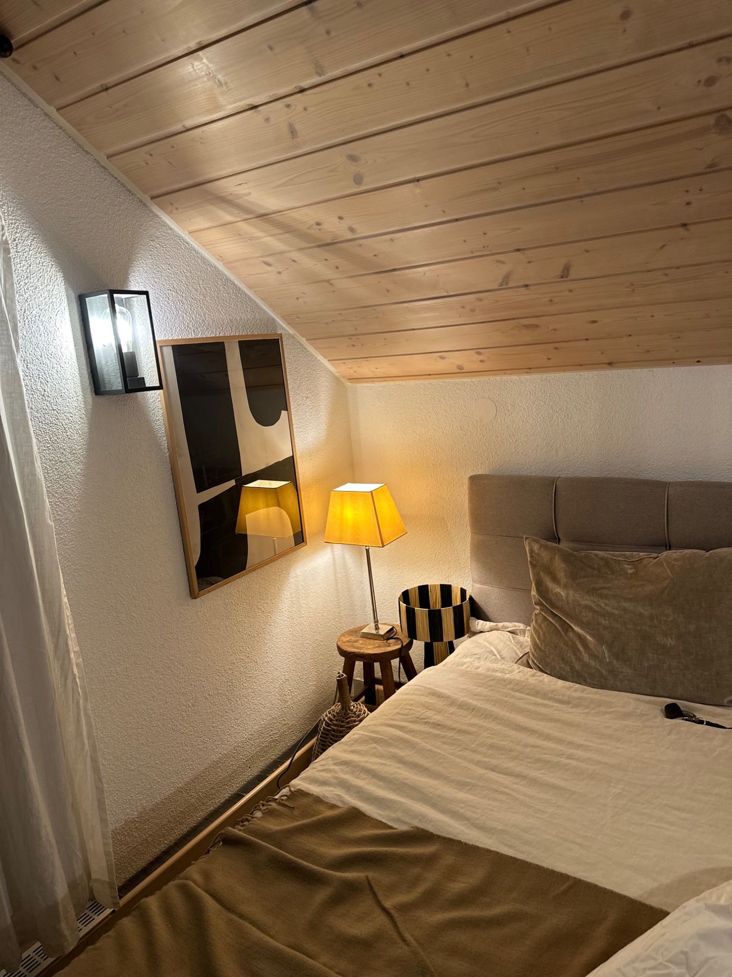 Schlafbereich mit Holzdecke und Lampe